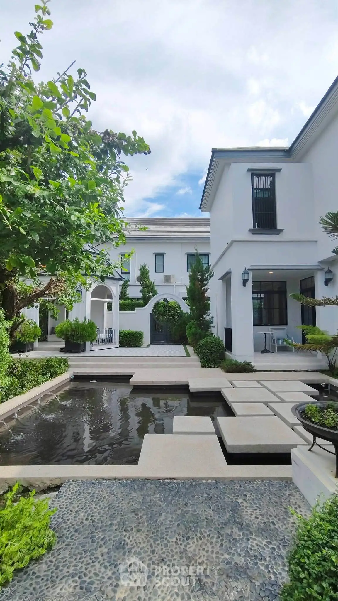 Luxurious modern villa with elegant garden and water feature, showcasing sophisticated architecture and serene outdoor space.
