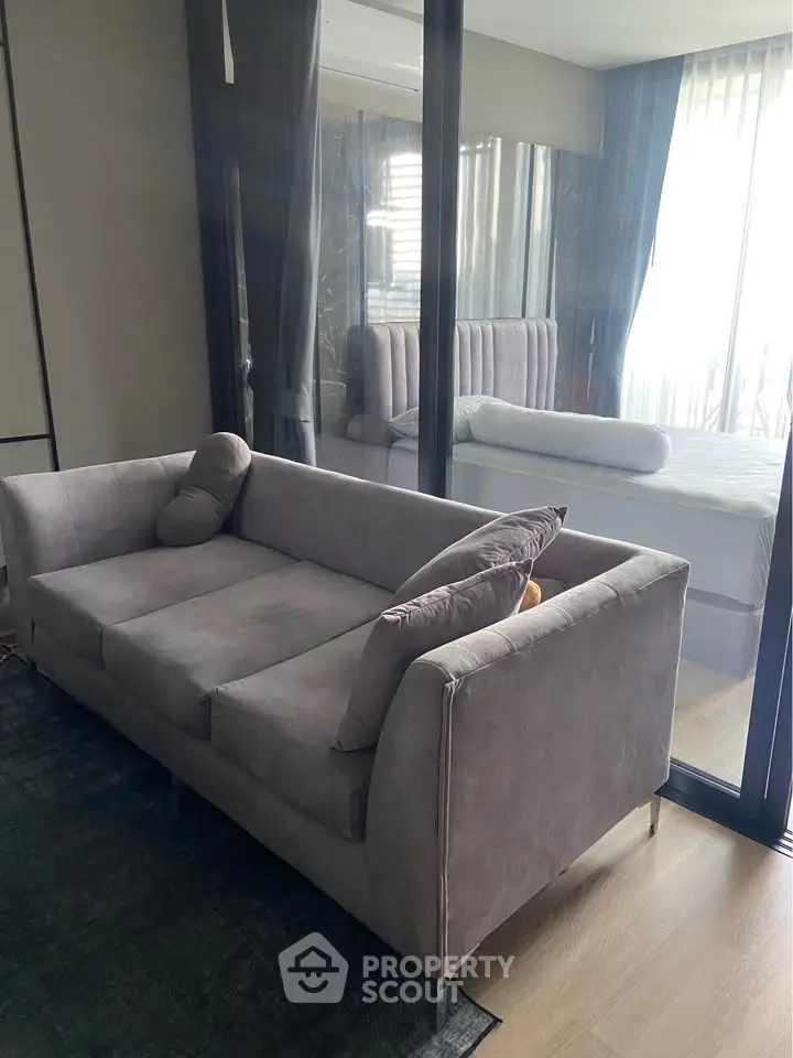 Modern apartment interior with stylish living room and bedroom separated by glass wall.