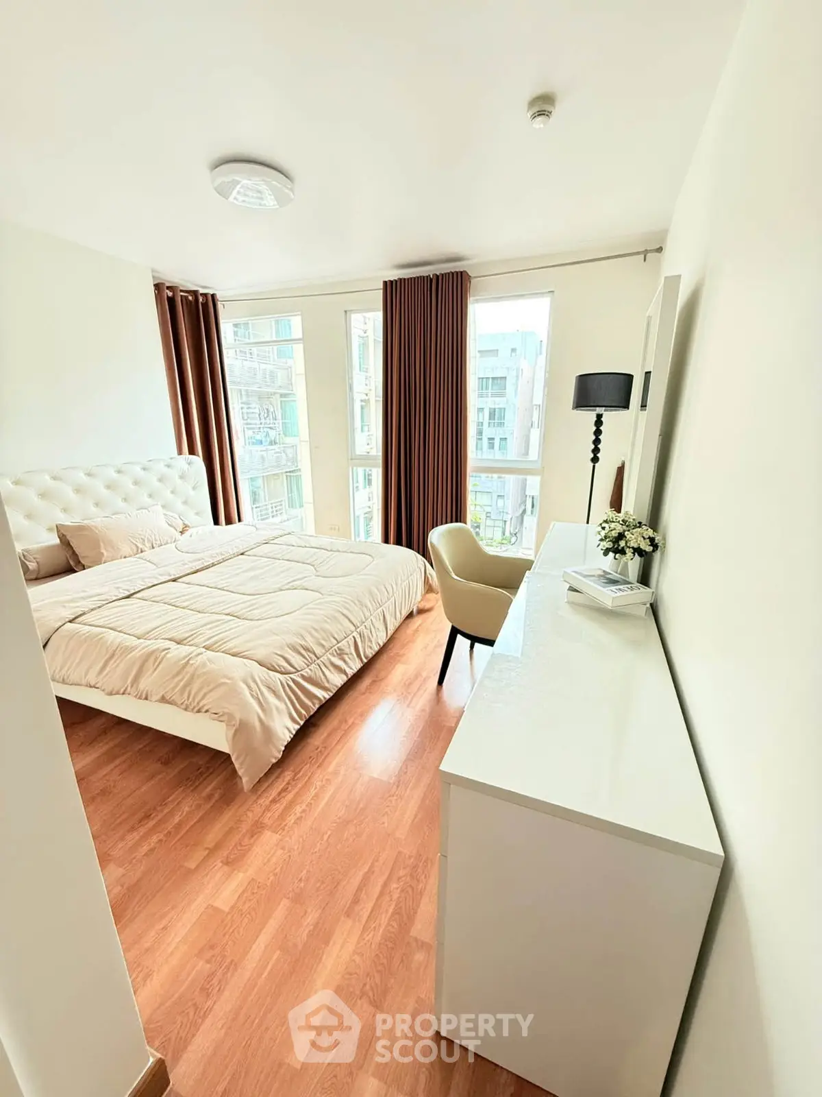 Bright and cozy bedroom with large windows and modern furnishings in a stylish apartment.