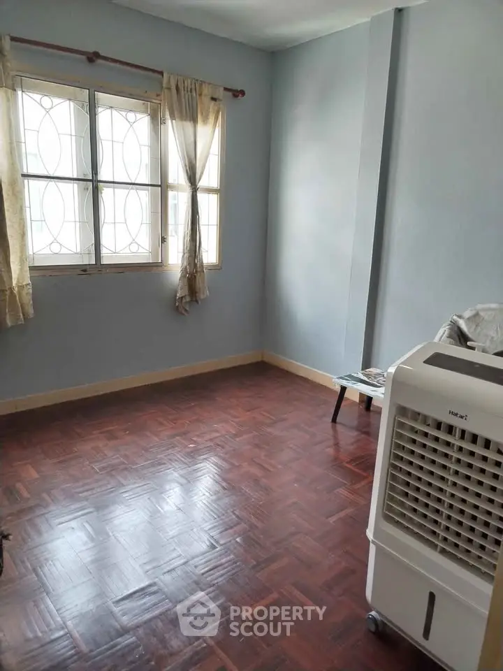 Spacious room with wooden flooring and large window, perfect for cozy living.