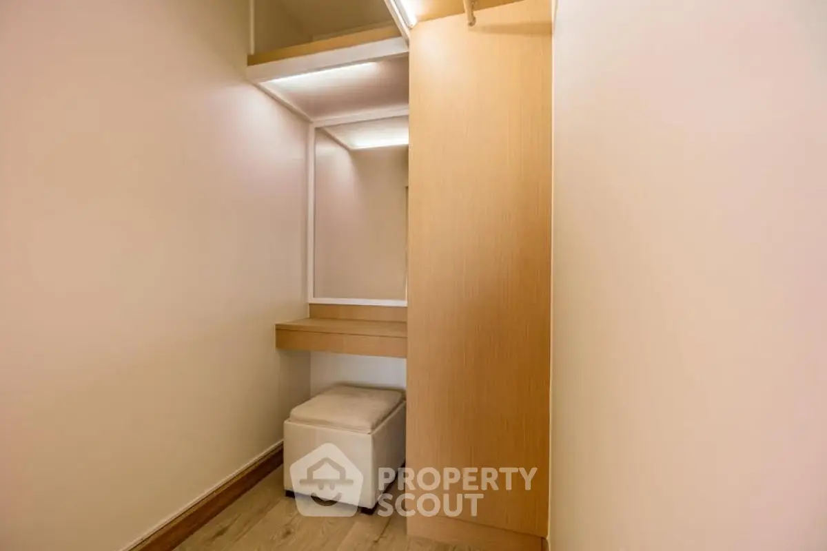 Spacious walk-in closet with modern wooden finishes and seating area.