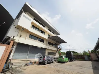 Modern industrial building with spacious parking area and sleek architectural design.