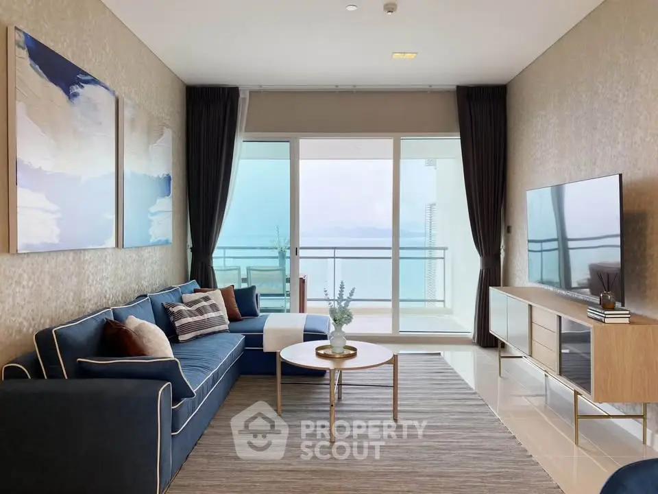 Modern living room with ocean view, stylish decor, and large glass doors leading to balcony.