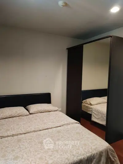 Cozy bedroom with elegant bedding and mirrored wardrobe in modern apartment.