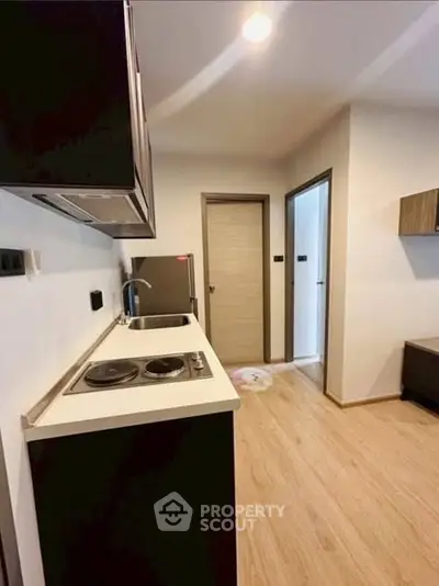 Modern compact kitchen with sleek design and electric stove in a cozy apartment.