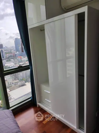 Modern bedroom with sleek wardrobe and city view from large window