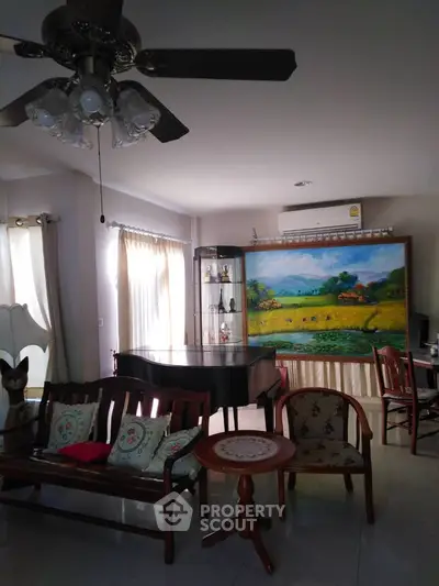 Charming living room with elegant decor and natural light, featuring a ceiling fan and artistic wall painting.