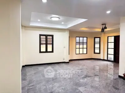 Spacious modern living room with elegant flooring and ample natural light.