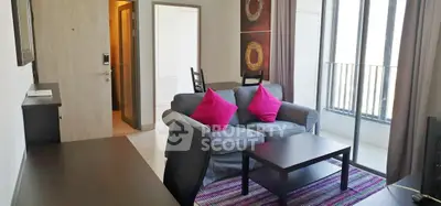 Modern living room with cozy sofa, vibrant decor, and large windows for natural light.