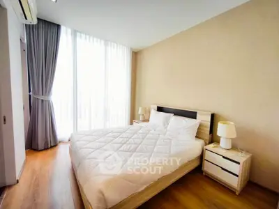 Spacious bedroom with large window and modern decor in a luxury apartment.