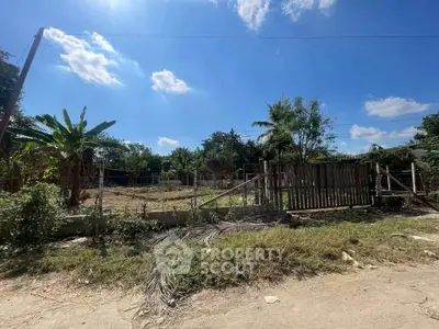 Spacious rural land plot with lush greenery and clear blue sky, perfect for development or agriculture.