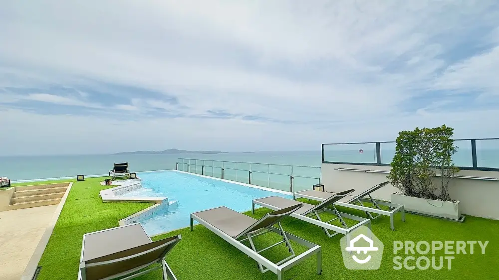 Stunning rooftop pool with ocean view and sun loungers on green terrace