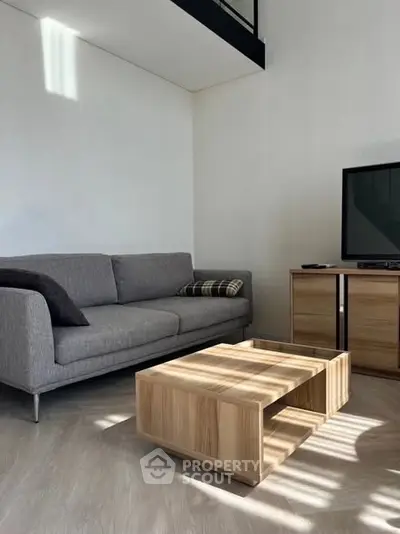 Modern living room with sleek gray sofa and wooden coffee table, perfect for cozy gatherings.