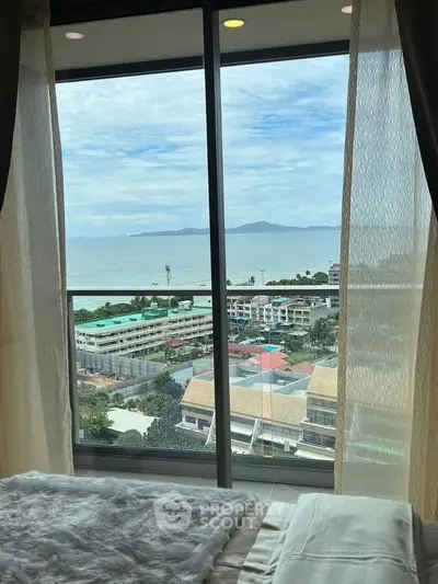 Stunning ocean view from a cozy bedroom with large windows and elegant curtains.