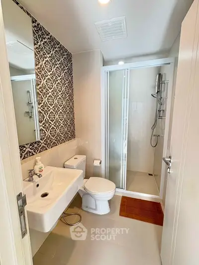 Modern bathroom with stylish tile accent wall and glass shower enclosure