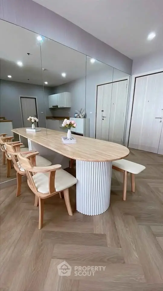 Modern dining area with elegant wooden table and chairs, mirrored wall, and stylish decor.