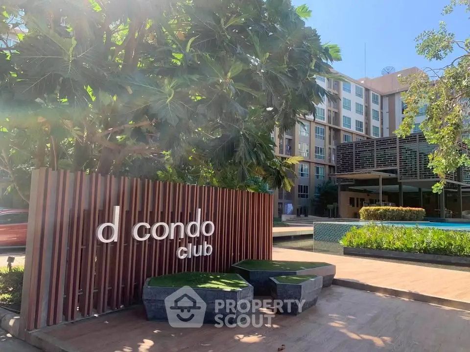 Modern condominium entrance with lush greenery and poolside view.