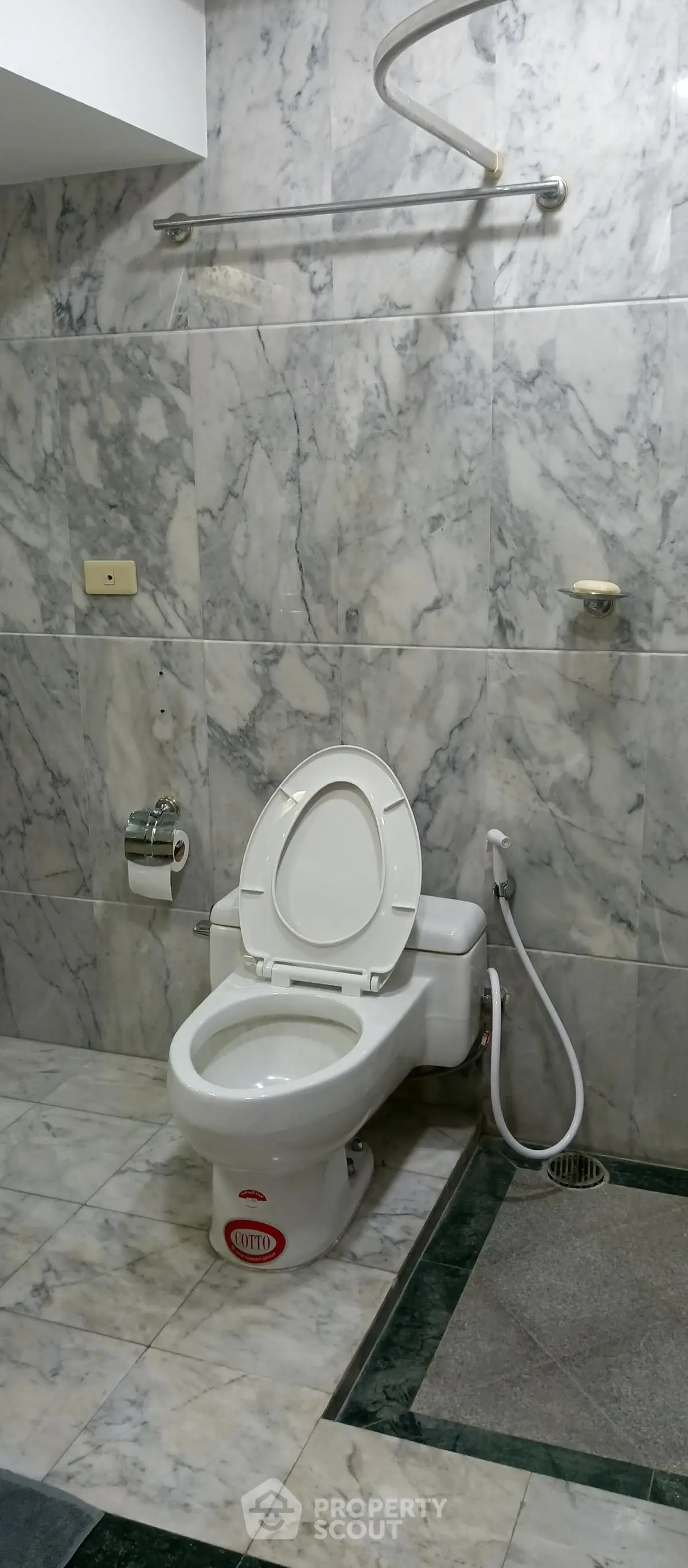 Spacious marble-tiled bathroom with modern toilet and bidet spray