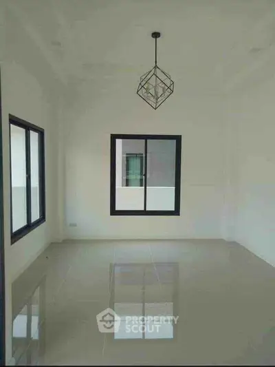 Spacious empty room with modern geometric pendant light and large windows