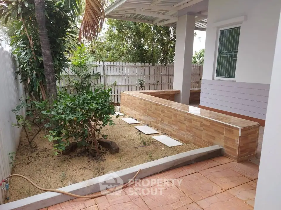 Charming garden area with tiled pathway and lush greenery in a cozy residential setting.