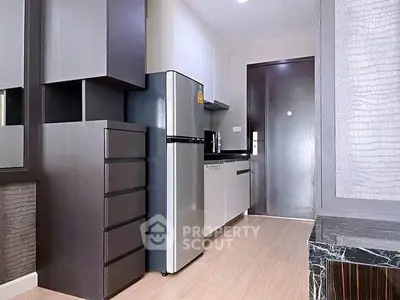 Modern kitchen with sleek cabinetry and stainless steel fridge in compact apartment.