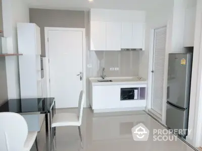 Modern kitchen with sleek white cabinetry and stainless steel appliances in a stylish apartment.