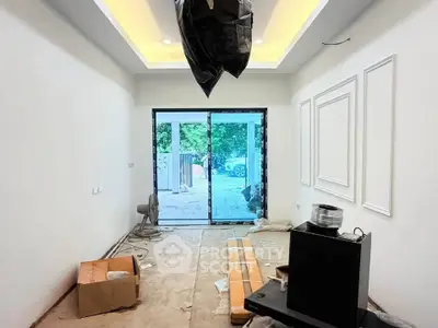 Spacious under-construction living room with modern ceiling lights and large sliding glass doors opening to a garden view.