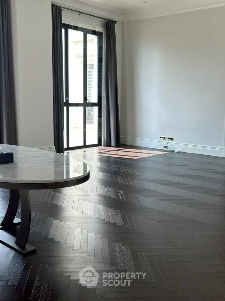 Spacious living room with elegant herringbone flooring and large window.