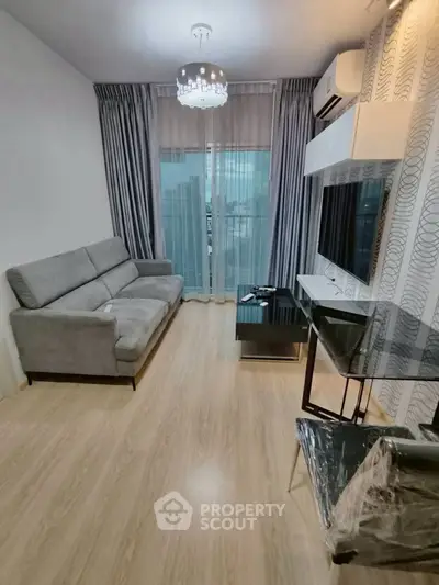 Modern living room with sleek furniture and large window offering natural light.