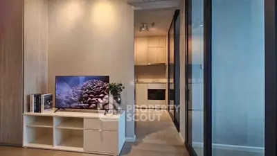 Modern living room with sleek TV stand and view into stylish kitchen