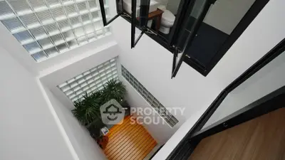 Modern home interior showcasing a high ceiling entryway with sleek black accents and a cozy sitting area, perfect for urban living.