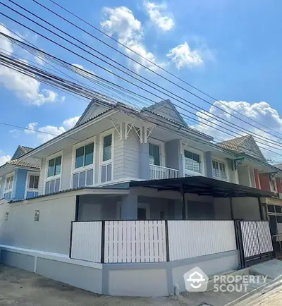 Charming two-story house with modern design and spacious balcony under clear blue skies.