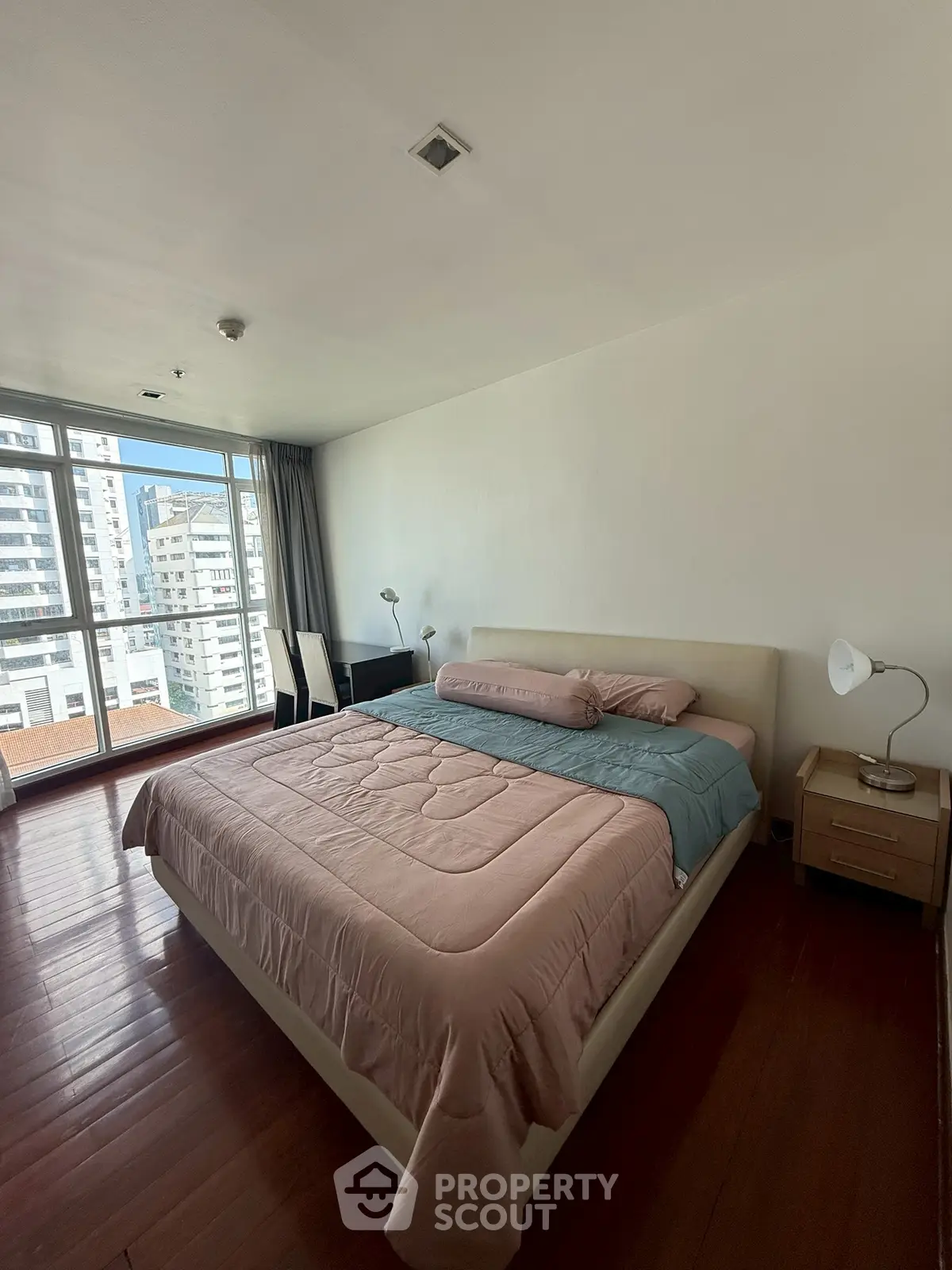 Spacious bedroom with large windows offering city views and modern furnishings.