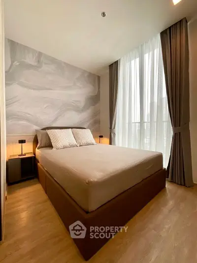 Modern bedroom with stylish decor and large window offering natural light