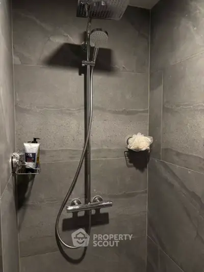 Modern bathroom shower with sleek gray tiles and chrome fixtures.