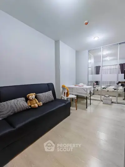 Modern living room with sleek black sofa and mirrored wardrobe, perfect for cozy urban living.