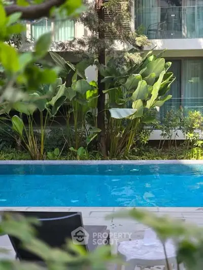 Luxurious apartment poolside view with lush greenery and modern design.