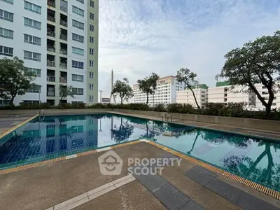 Stunning poolside view at modern residential complex with cityscape backdrop.