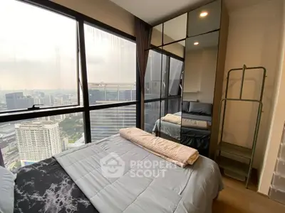Modern bedroom with city view and mirrored wardrobe in high-rise apartment.