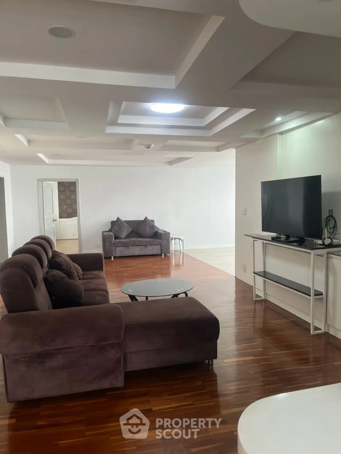 Spacious living room with modern furniture and wooden flooring, perfect for relaxation and entertainment.
