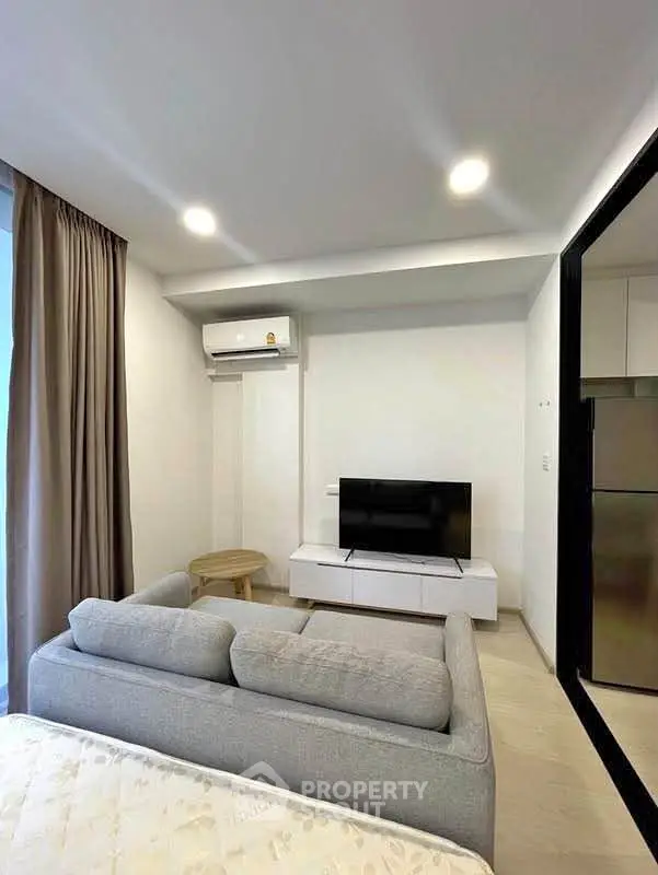 Modern living room with sleek design, featuring a cozy sofa, flat-screen TV, and air conditioning for comfort.