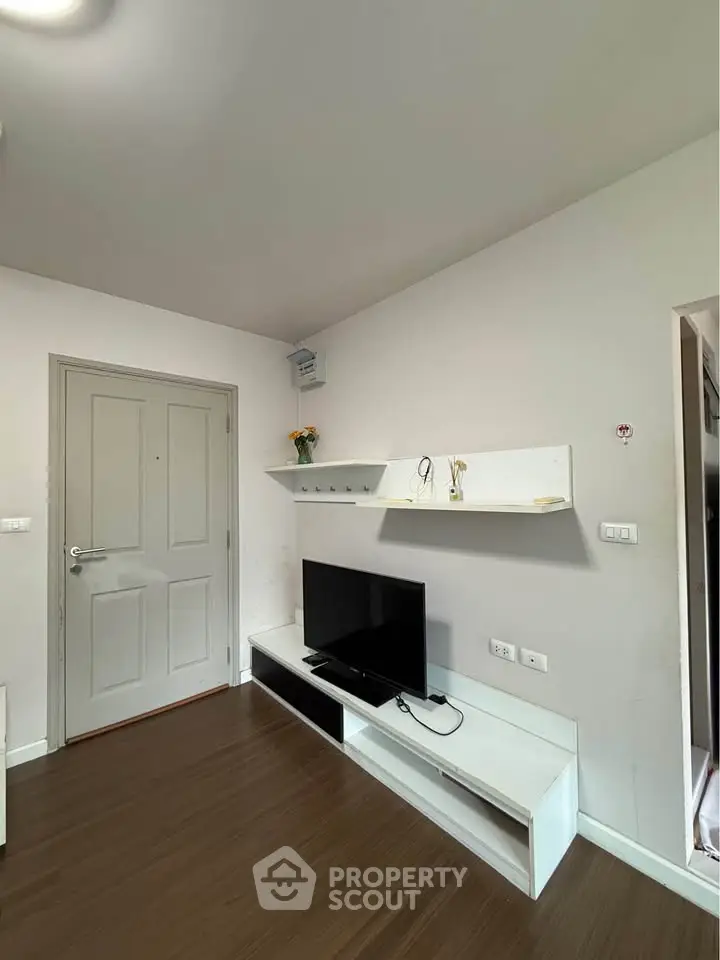 Modern living room with sleek TV stand and wall-mounted shelves, featuring minimalist decor and wooden flooring.
