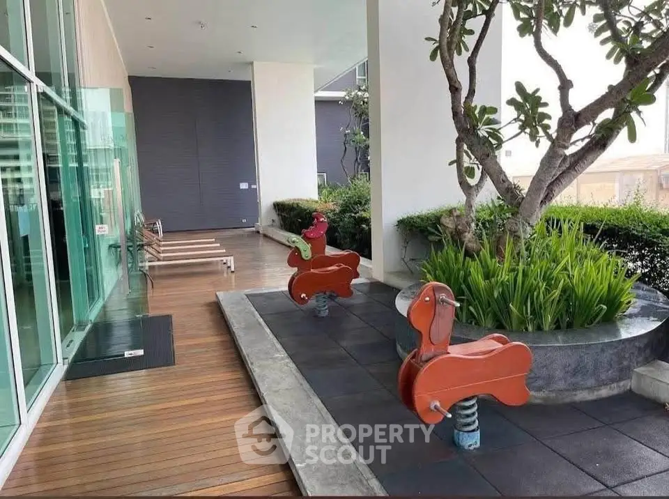 Modern outdoor play area with spring riders and lush greenery in a residential complex.