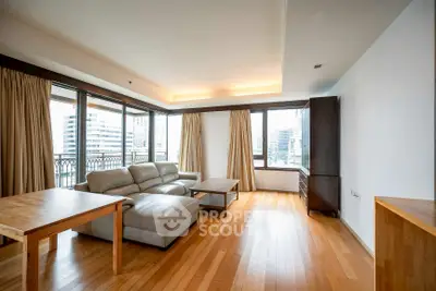 Spacious living room with hardwood floors and large windows offering city views.