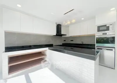 Modern kitchen with sleek black countertops, built-in oven, and minimalist white cabinetry.