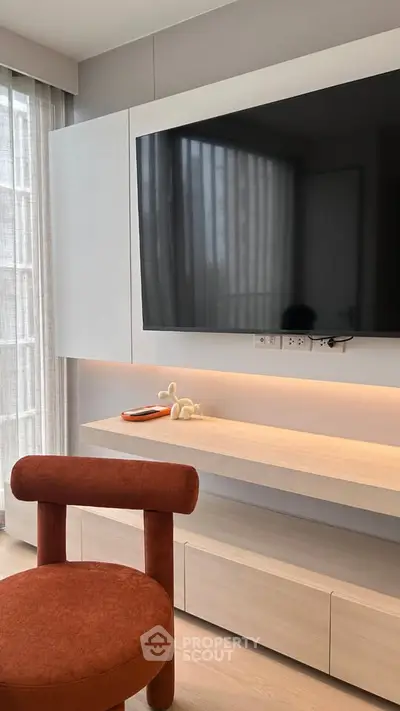 Modern living room with sleek TV setup and stylish red chair