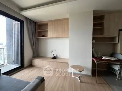 Modern living room with wooden flooring and built-in storage, featuring a large window with city view.