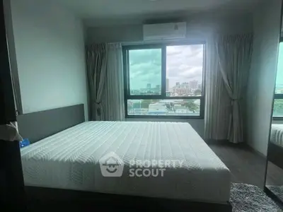 Spacious bedroom with large window offering city views, featuring a comfortable bed and modern decor.
