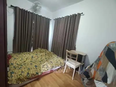 Cozy bedroom with wooden flooring and large windows covered by curtains, featuring a small desk and chair.