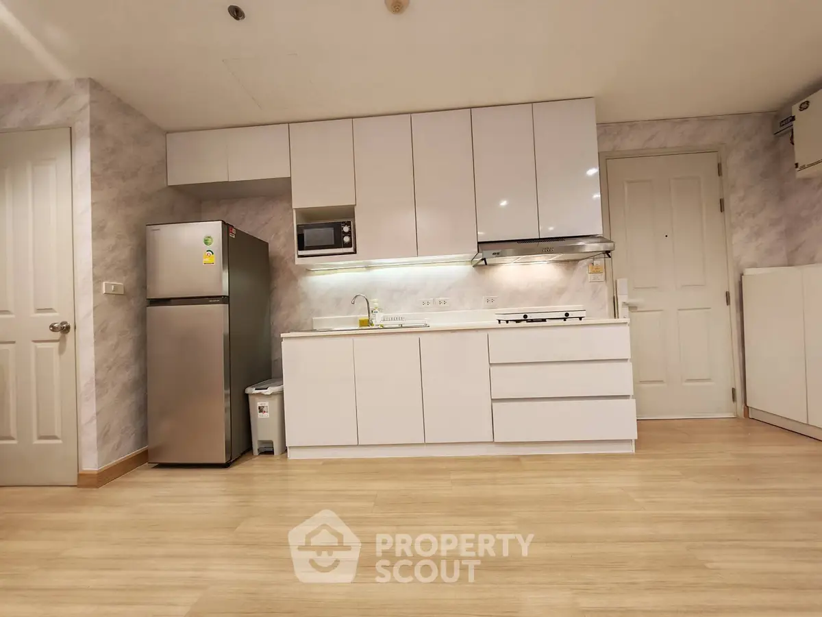 Modern kitchen with sleek white cabinets and stainless steel appliances in a spacious apartment.